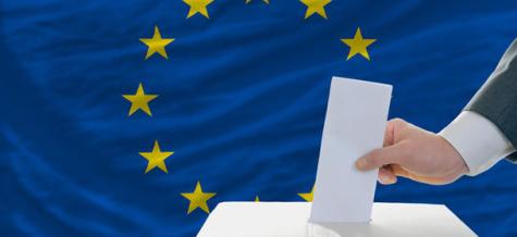 A man puts his ballot in a box during elections in Europe in front of the EU flag