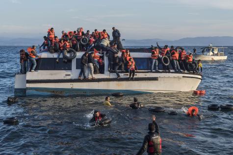 Syrians and Iraq refugees arrive to the island of Lesbos, Greece by boat. Many are swimming in the water and they are all weating orange life vests