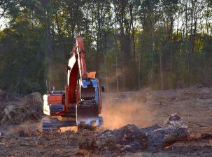 An industrial size orange digger is working to tear down trees in the Amazon rainforest. 