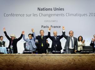 Different politicians from around the world wearing suits standing and holding hands in the air whilst smiling