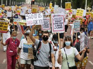 Many people march down the streets of London in protest of low pay for NHS workers.