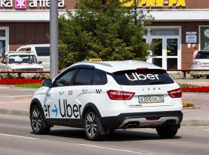 White Uber taxi drives down a quiet street