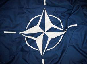 The flag of the North Atlantic Treaty Organization (NATO) consists of a dark blue field charged with a white compass rose emblem, with four white lines radiating from the four cardinal directions.