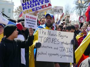 Protesters demand an end to the Presidency of Maduro. Many pro-human rights signs are held in the air as well as Venezuelan flags and a mega phone