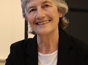 Image of new Irish President Catherine Connolly wearing a black suit. She is smiling warmly at the camera.