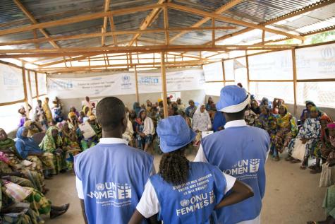 3 UN Women Humanitarian Workers stand infront of a group of seated female refugees in Cameroon