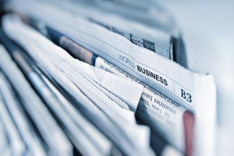 Many newspapers sit stacked side by side