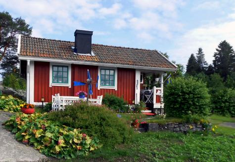 Beautiful red tiny home surrounded by a lush garden