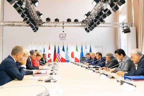 A G7 working lunch in France see's leaders sitting around a white table with each of the countries flags in the background