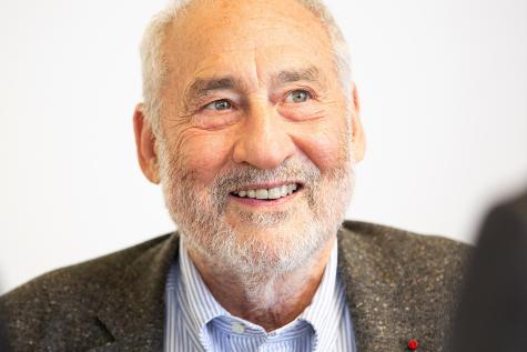 Image on Nobel prize winner economist Joseph E. Stiglitz. An older gentleman with grey hair, wearing a grey suit smiles warmly at the camera