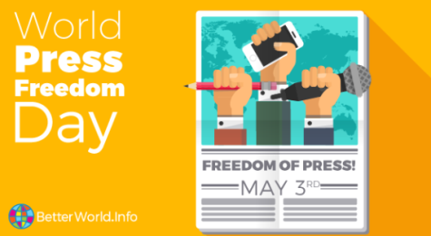 Yellow poster for World Press Freedom Day on May 3rd, the day and date is written on the left hand side and the main poster is a newspaper front page with fists in the air holding microphones, pens, and a phone