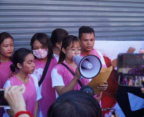 Image of Mother Nature a group of Cambodian activists from Cambodia. Four young activists are covered in food colouring representing blood. One of them holds a megaphone.