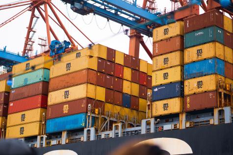 Different coloured shipping containers sit stacked ontop of each other on a freight ship