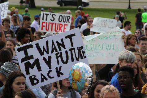 Many children are gathered at a climate strike, they hold large signs which say 'I want my future back' and 'It's our future'