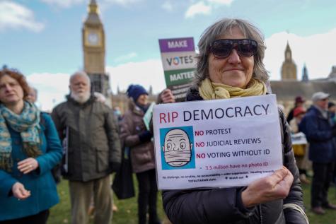 Protesters gather outside the British parliament to demand the government drop its proposed Elections Bill. A woman wearing sunglasses holds a sign which reads 'RIP Democracy'