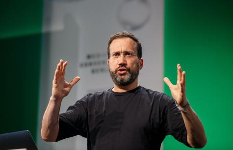 Forensic Architecture founder Eyal Weizman speaks at a conference. The British Israeli political activist is wearing a black tshirt and a microphone