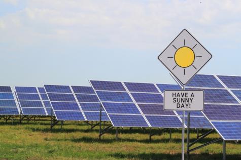 The Dunayskaya Solar Station - Many solar panels sit on a green field with a sign infront with a picture of a sun that reads 'Have a sunny day'