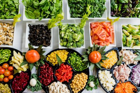 Lots of bowls of colourful healthy food sit on top of a table