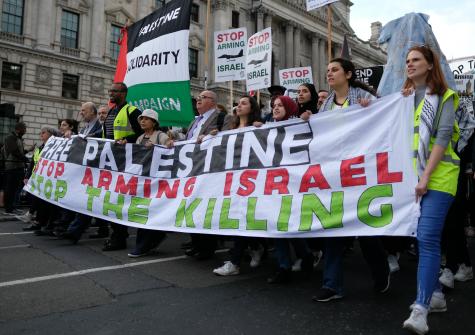 Palestine solidarity protesters march towards the British parliament on 5 June 2018 holding a sign that says 'Free Palestine, stop arming Israel, stop the killing' 