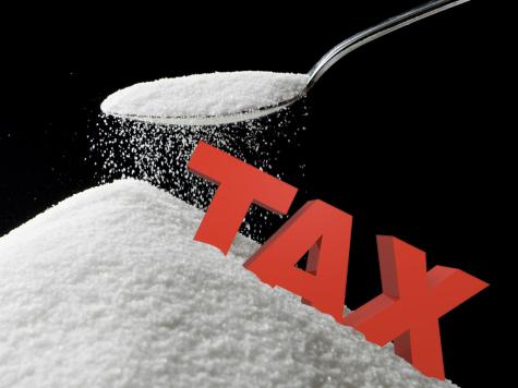 Large red letters spell out the word tax on a large pile of sugar