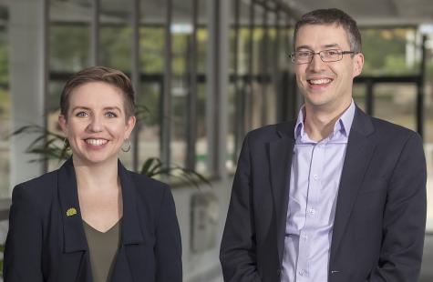 Image of Green Party co-leaders Carla Denyer and Ross Greer. Both are wearing black suits and are smiling at the camera