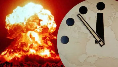 A red atomic bomb cloud looms in the distance while a large white clock fills the right side of the image. The clock hands are pointing at a few seconds before midnight