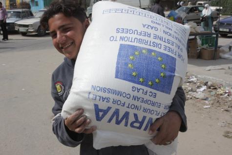 A young UNRWA worker carries a large white sack of flour helping to support Palestinian refugees