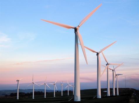 Sunset at Royd Moor Wind Farm. Many white wind turbines in a field under the pink glow of a sunset.