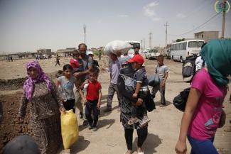 Relief effort for Syrian refugees in a refugee camp in Northern Iraq. Various families carry their possessions on a dirt road